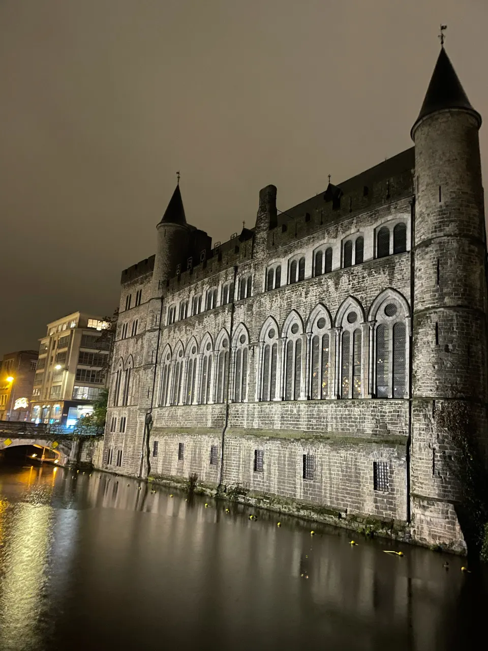 Oud gotisch gebouw aan het water in Gent, verlicht en weerspiegeld in de Leie