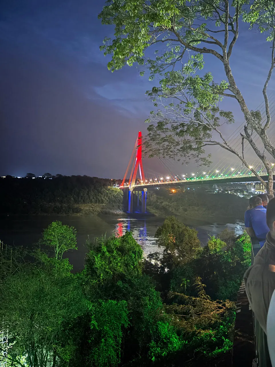 De verlichte brug bij het drielandenpunt van Foz do Iguaçu in de avond