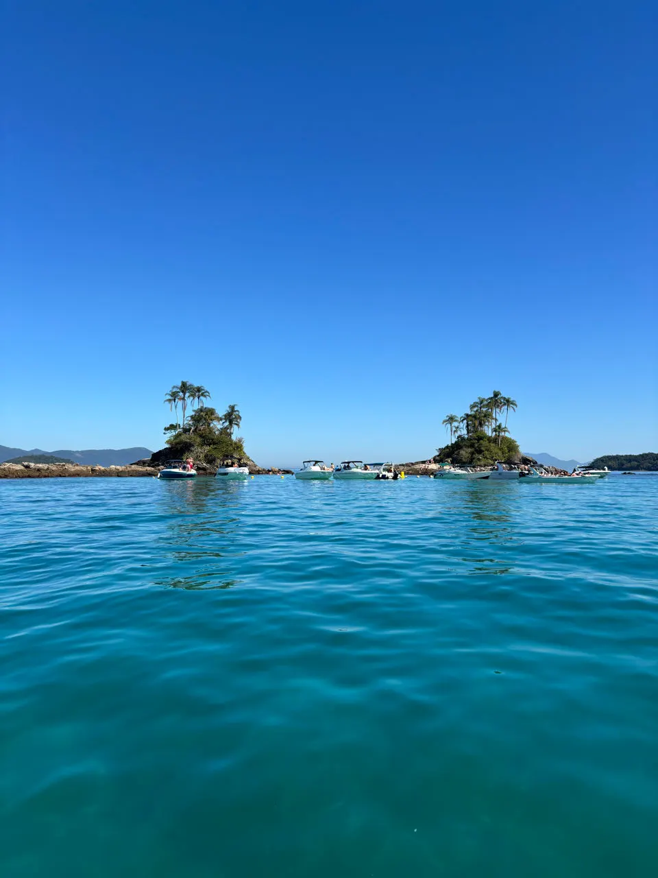 Kristalhelder blauw water met een eilandje tijdens de boottour bij Ilha Grande