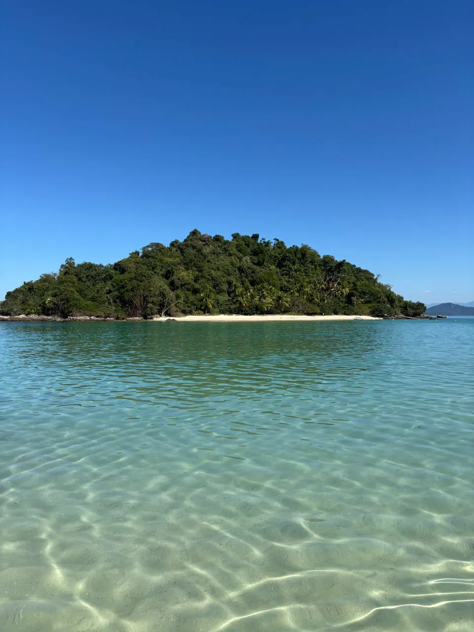 Een klein groen eilandje in azuurblauw water bij Ilha Grande