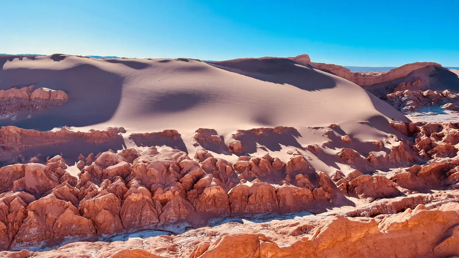 Golvende rode duinen en rotsen in de Valle de la Luna bij zonlicht