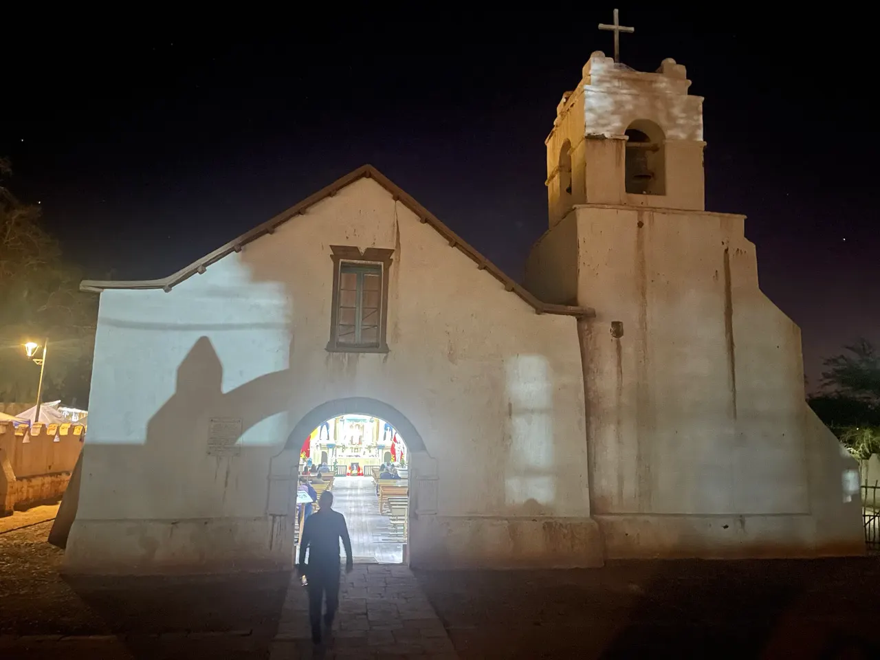 Het verlichte witte kerkje van San Pedro de Atacama in de avond