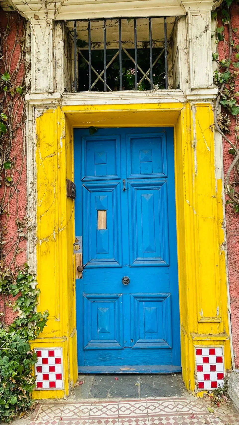 Felgele muur met een blauwe deur in een straat van Valparaíso