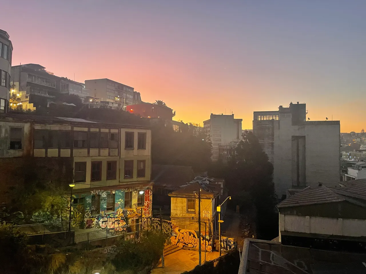 Zonsondergang met warme kleuren boven de heuvels en huizen van Valparaíso