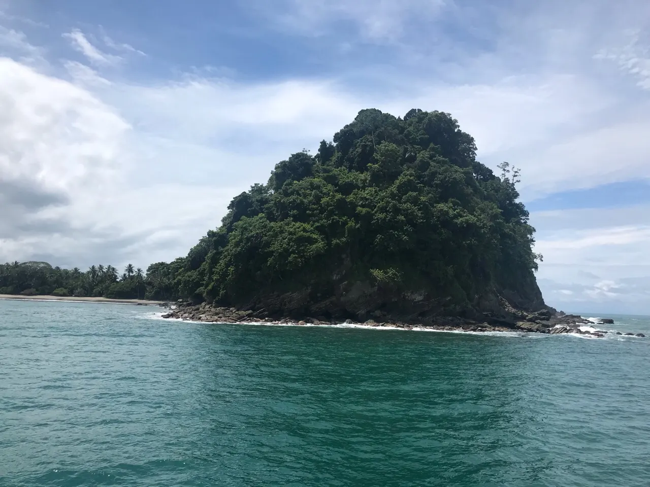 Een groen begroeid rotseiland in zee gezien vanaf een boot bij Manuel Antonio