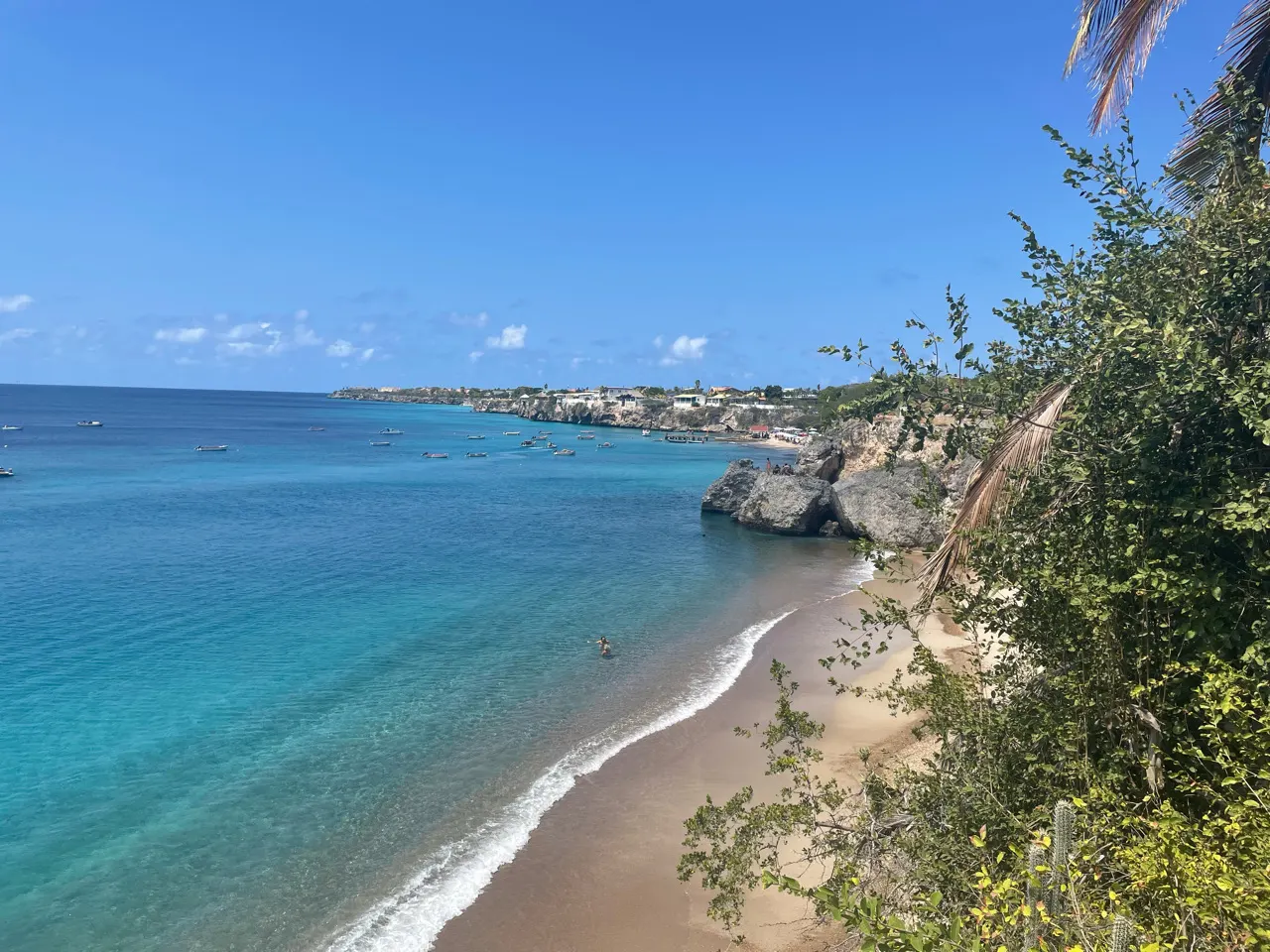 Felblauwe baai met wit strand en rotsen aan de westkant van Curaçao
