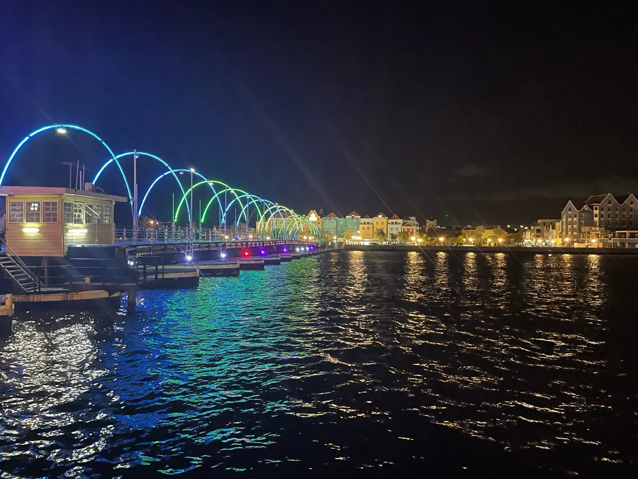 De verlichte Emmabrug over de baai in Willemstad bij avond