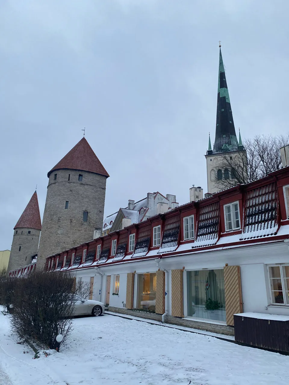 De besneeuwde stadsmuur met torens en rode daken van de oude stad van Tallinn