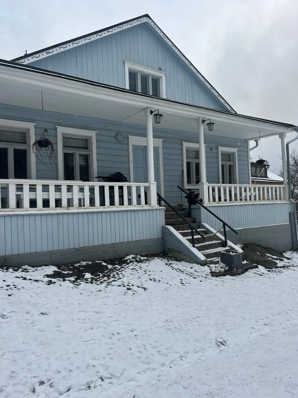 Een lichtblauw houten huis met veranda in de sneeuw op Suomenlinna