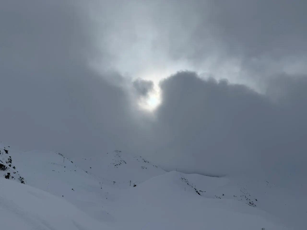 De zon breekt door de wolken boven de besneeuwde bergen van Les Arcs