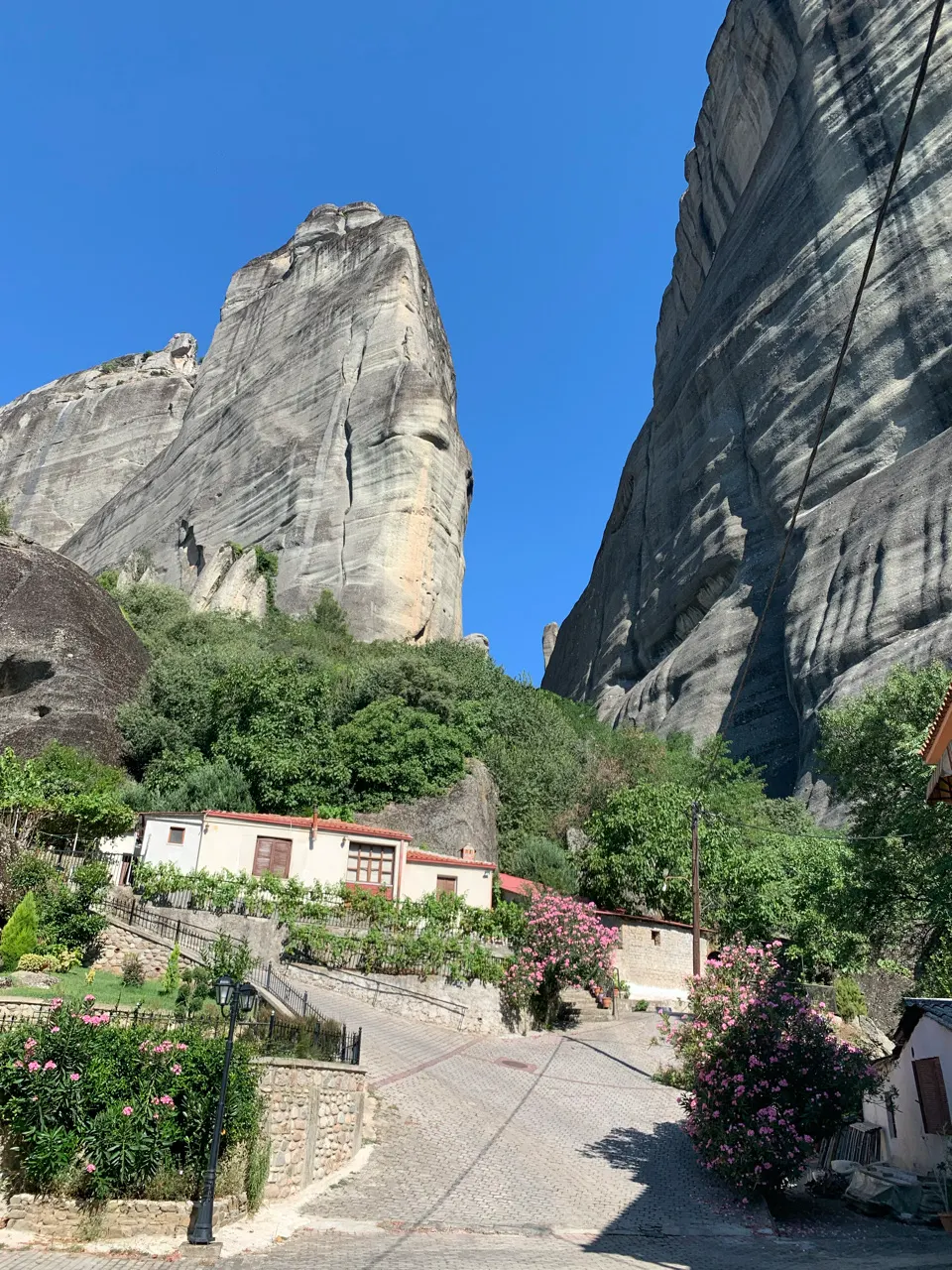 Klooster hoog op een rots met een huisje eronder in Meteora