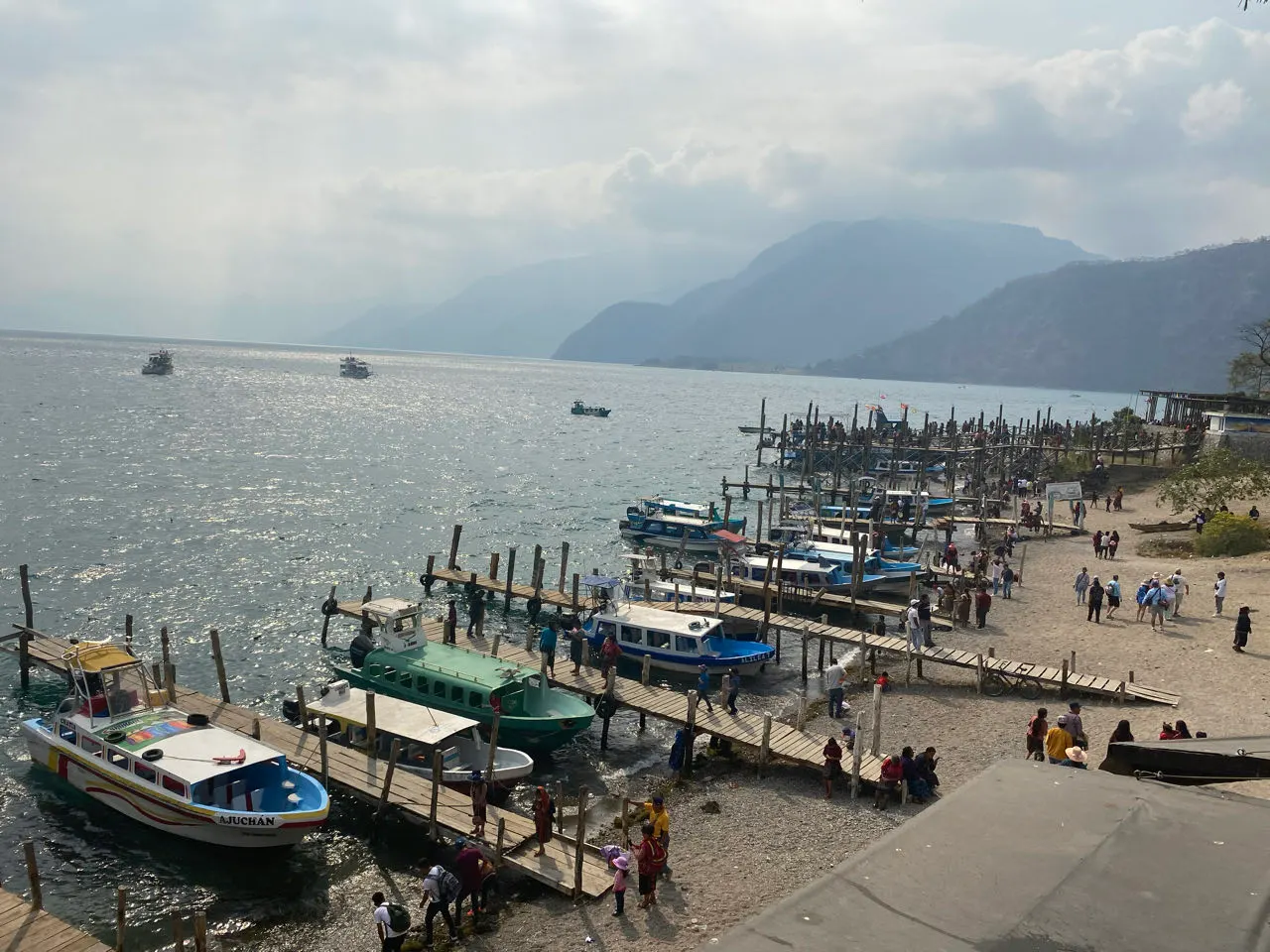 Boten aan de oever van het Lago de Atitlán met vulkanen aan de overkant van het meer