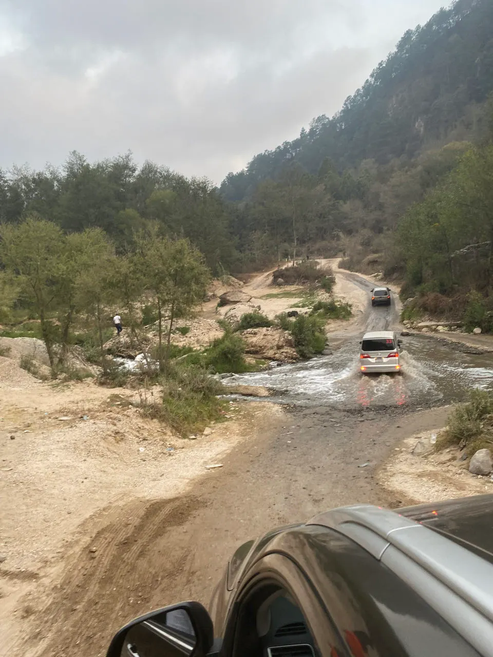 Een auto steekt een riviertje over bij een ingestorte brug op weg naar Atitlán