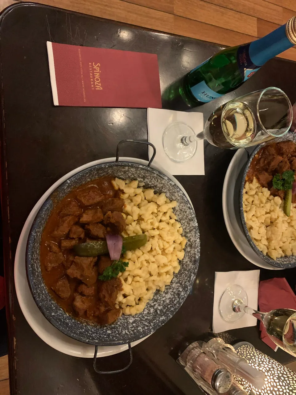 Een kom Hongaarse goulash met een glas wijn op een houten tafel