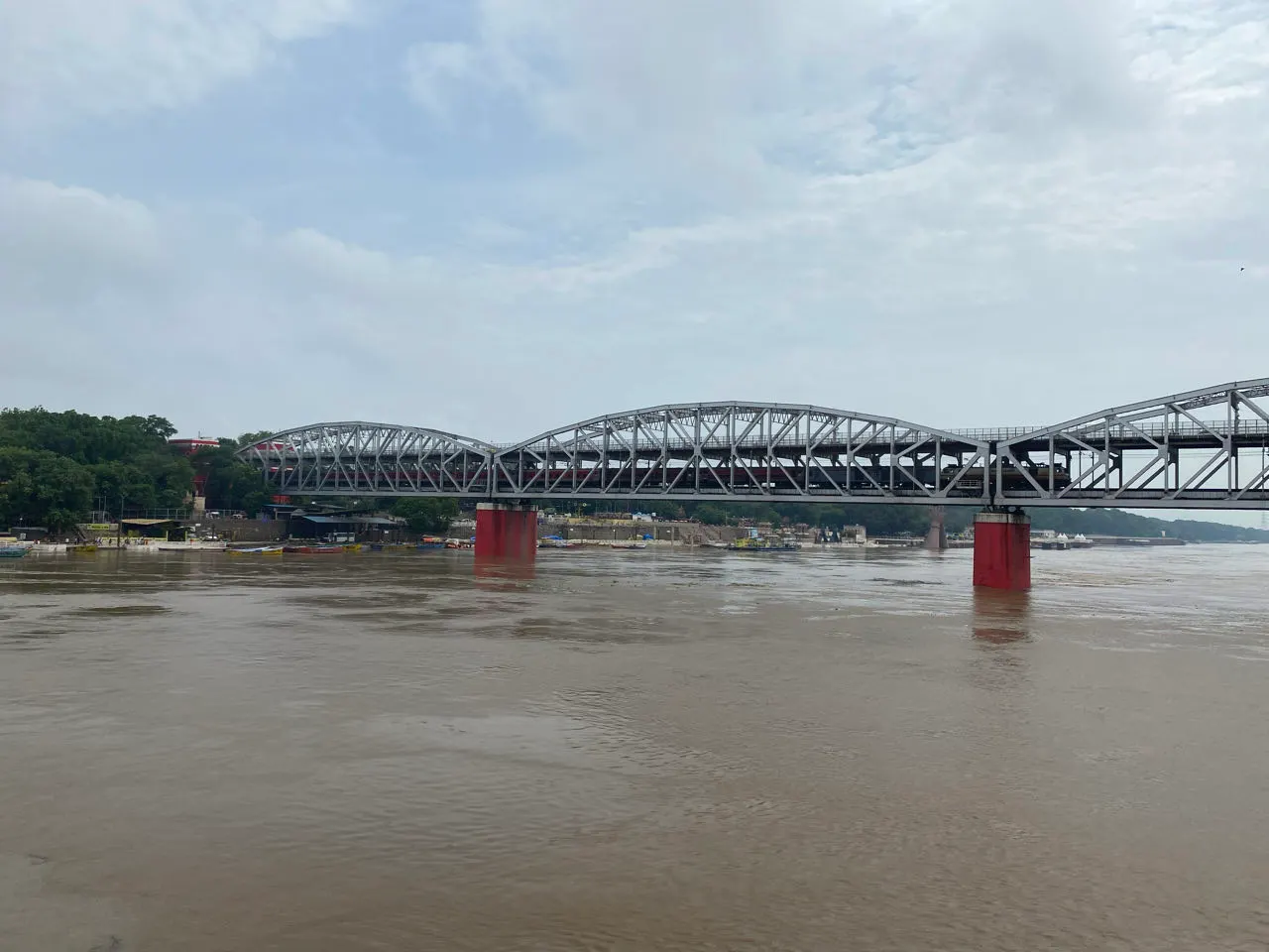 Een oude brug over de brede, bruine Ganges bij Varanasi