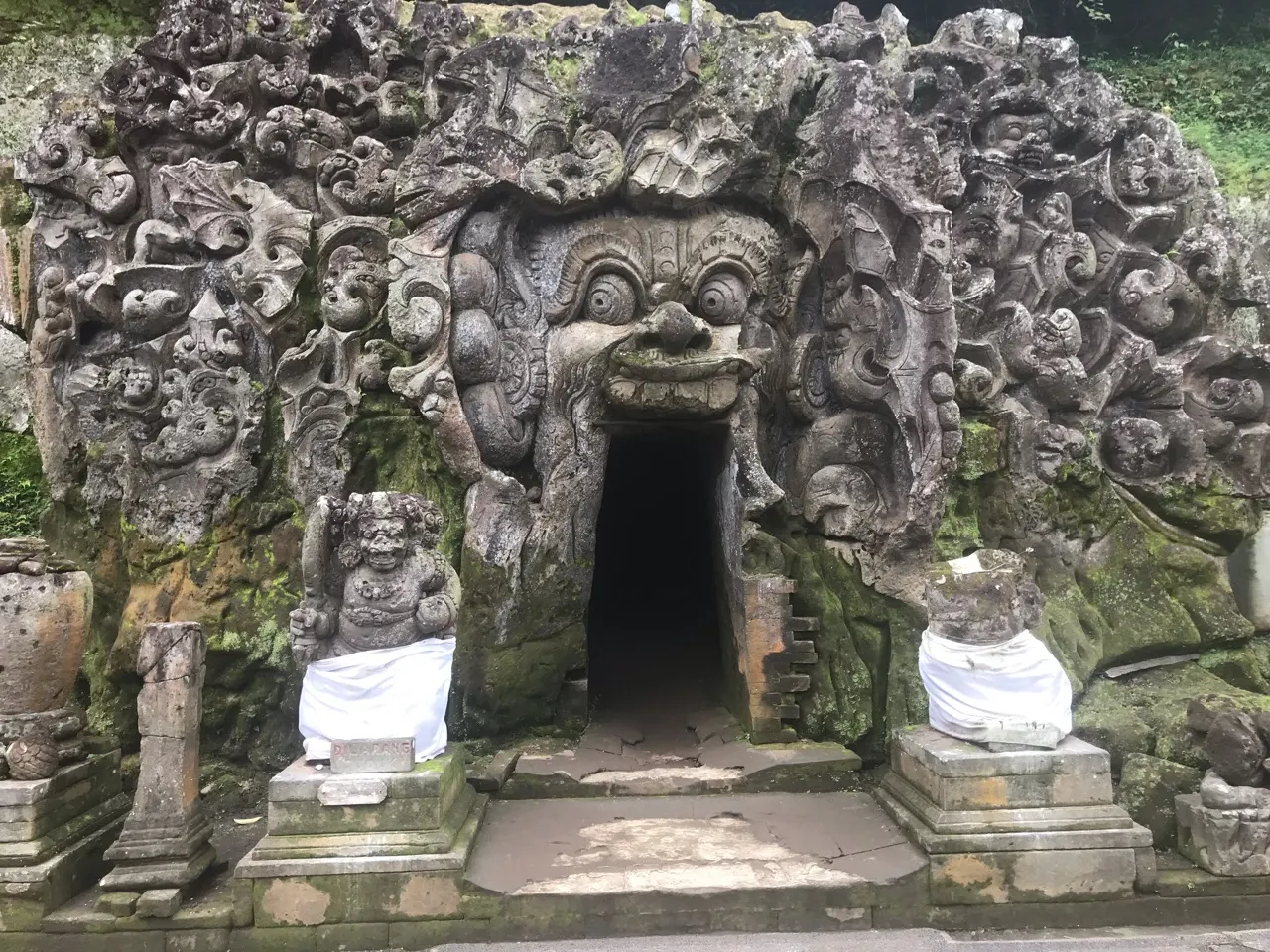 De ingang van de Goa Gajah olifantsgrot met gebeeldhouwd gezicht in de rots