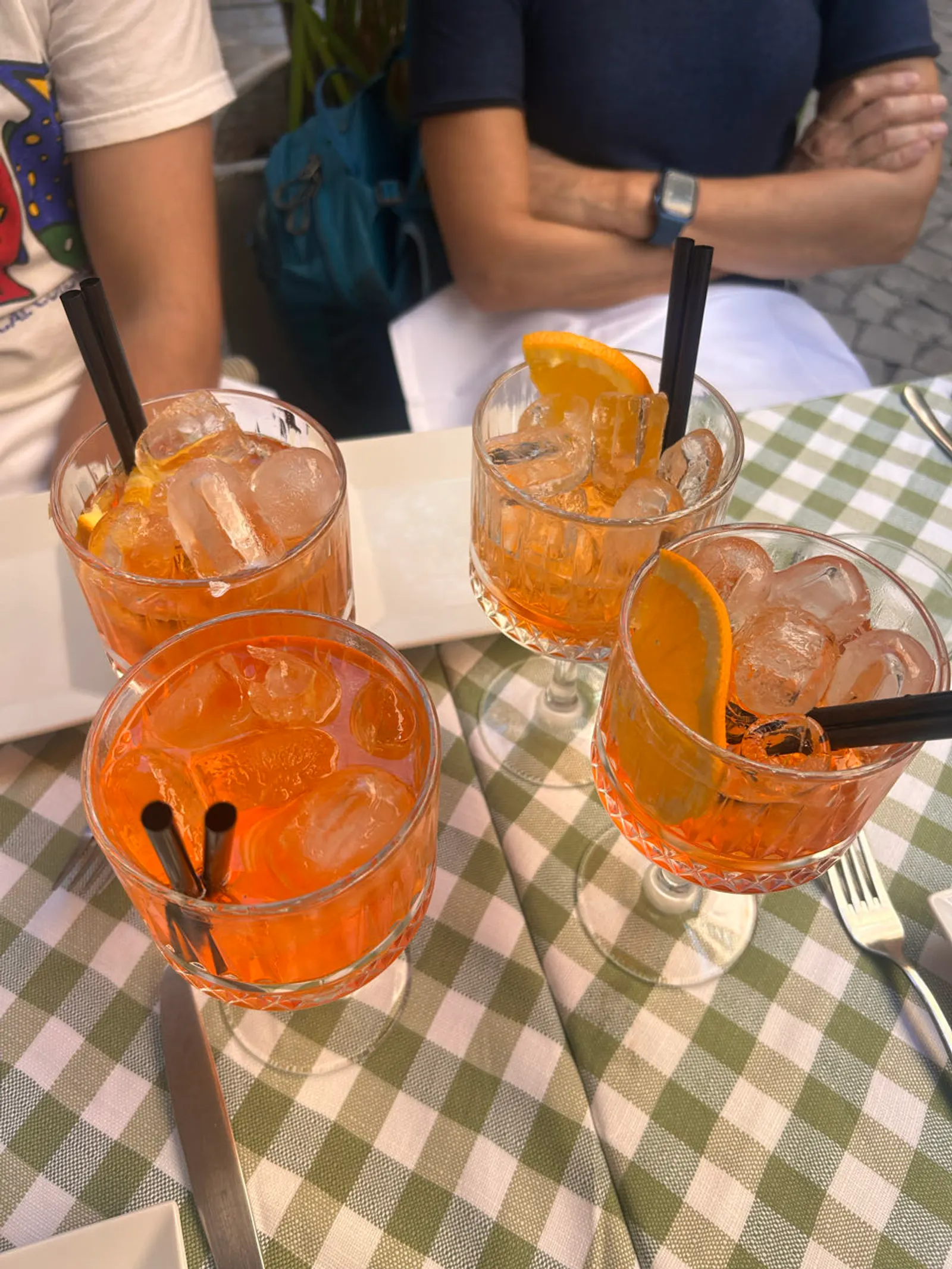 Twee glazen aperol spritz op een geruit tafelkleed op een terras in Rome
