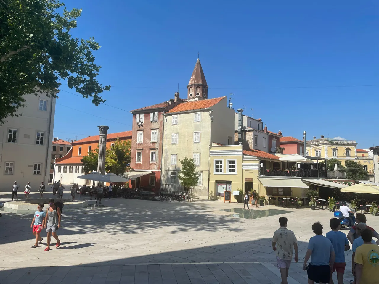 Een plein in de oude stad van Zadar met een kerktoren en terrasjes