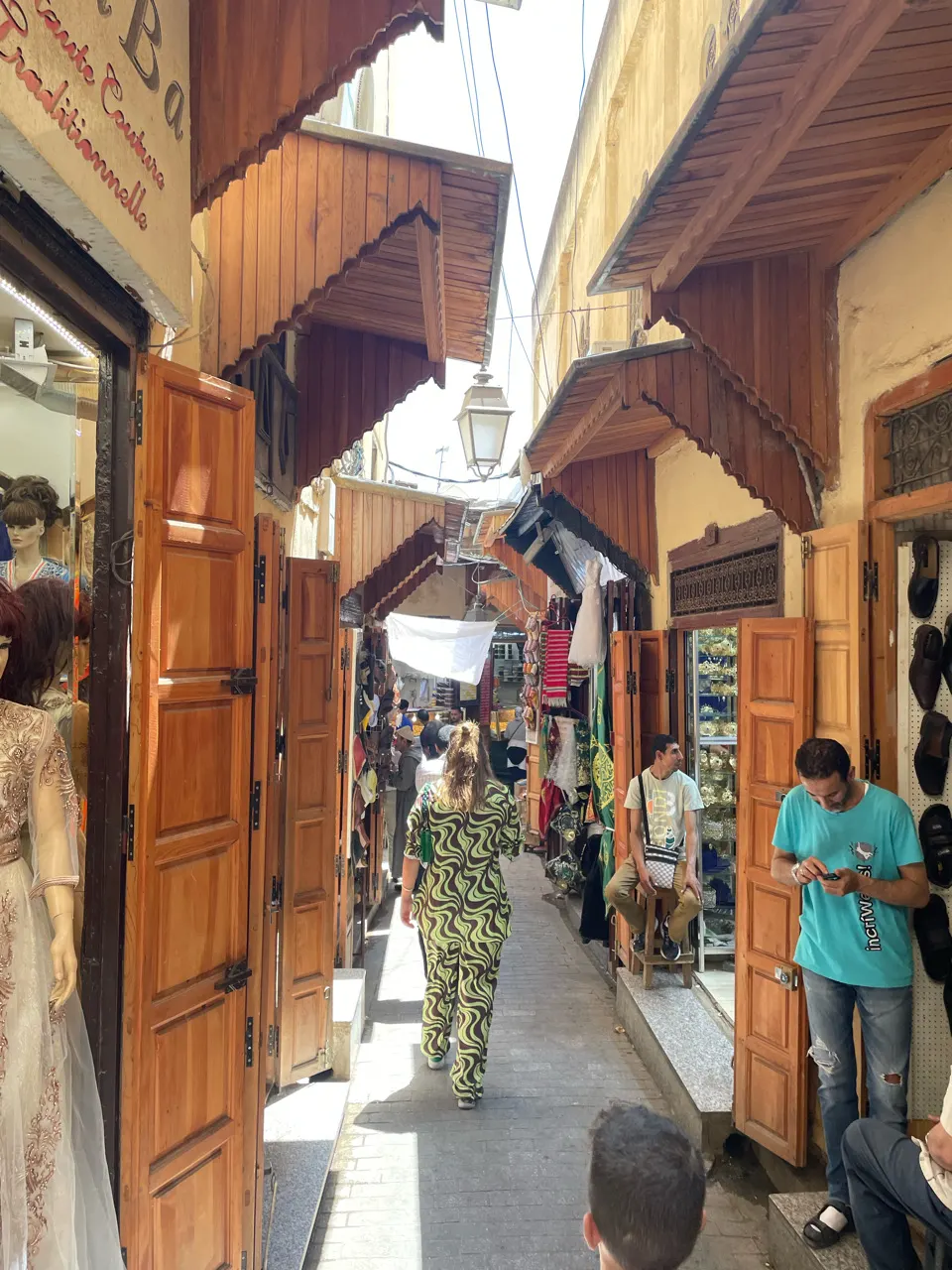 Een drukke winkelstraat met kraampjes in de souks van Fes