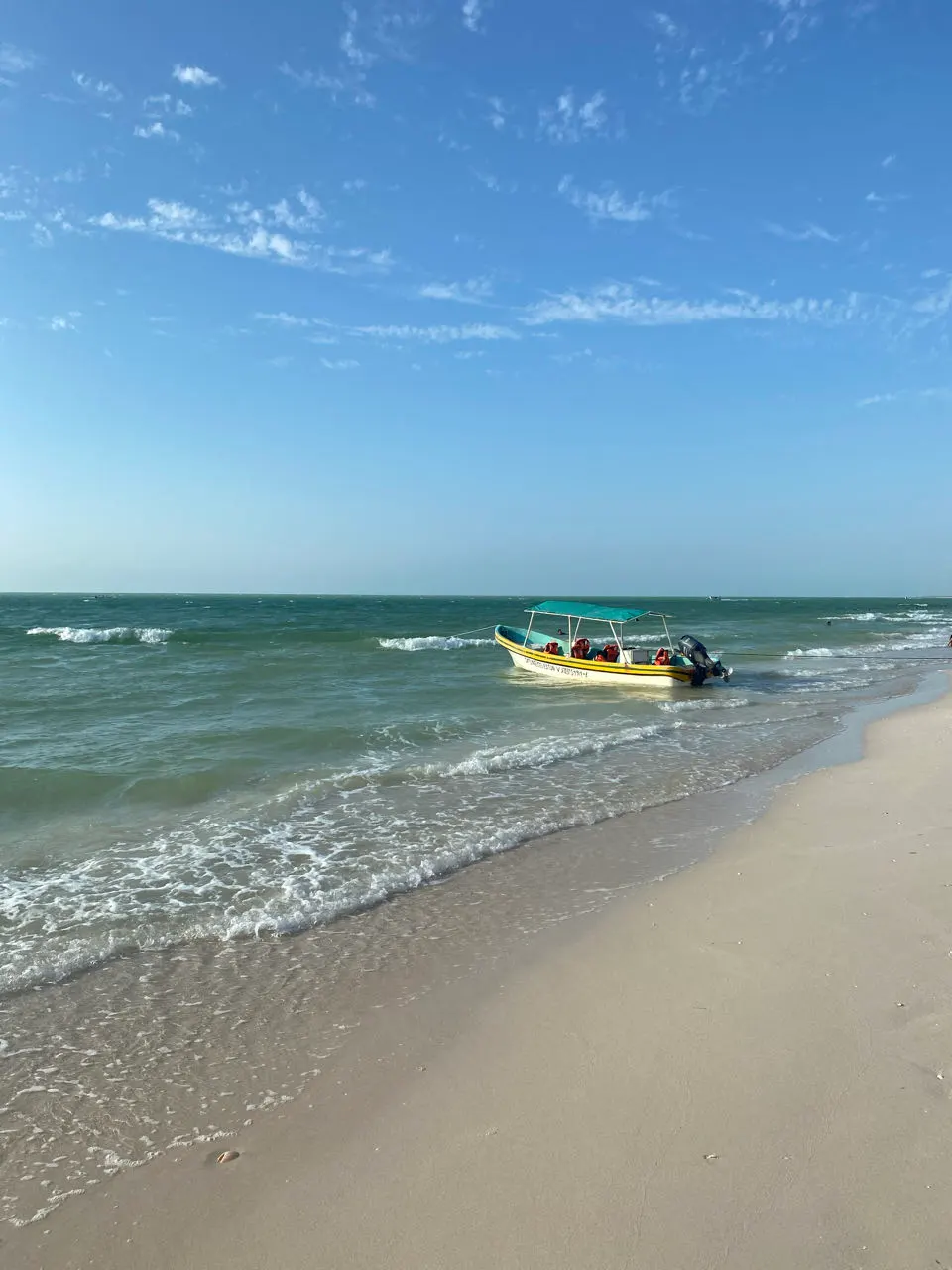Golven op het strand van Celestún met een bootje in de branding