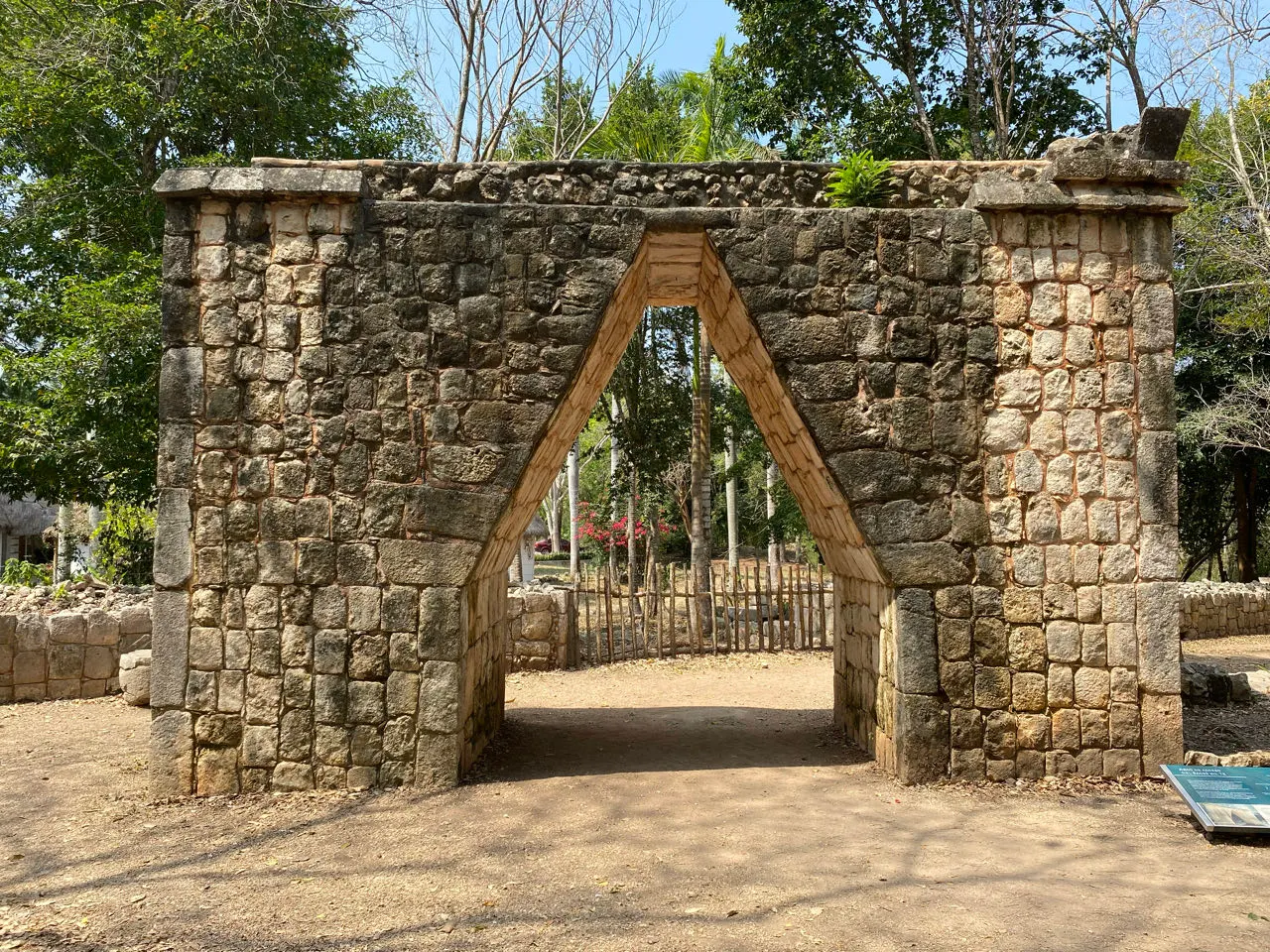 Oude stenen boog en ruïne tussen de bomen bij Chichén Itzá