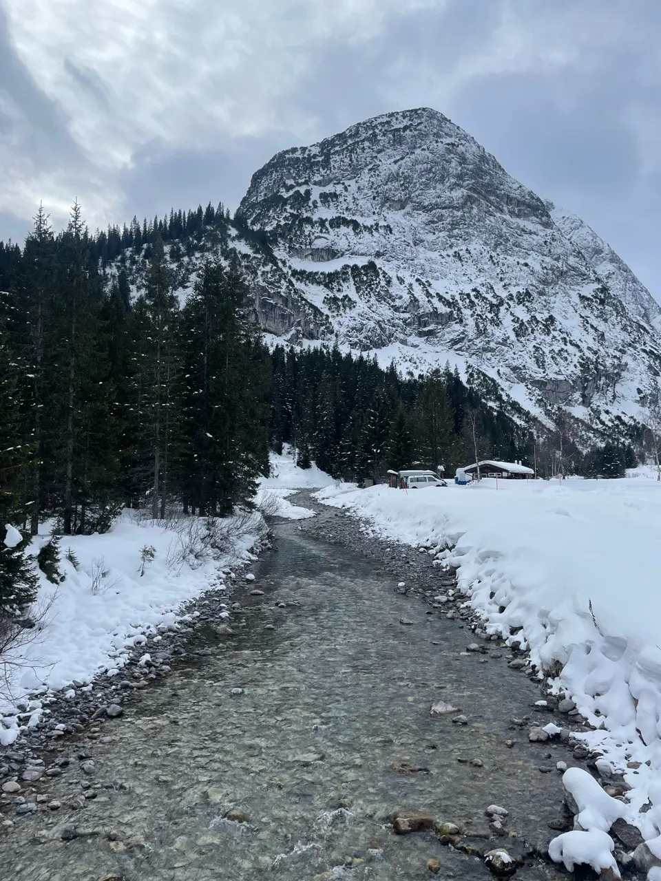 Besneeuwd wandelpad tussen hoge sneeuwwallen met bergen erachter