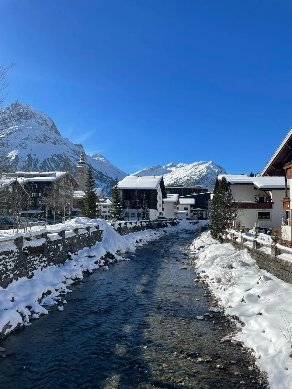Besneeuwde straat met chalets in Lech onder een blauwe lucht