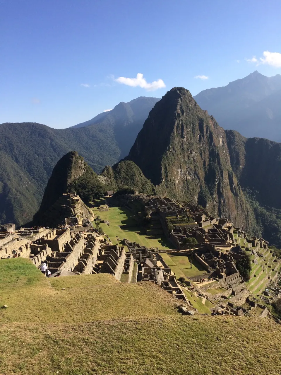 Klassiek uitzicht op Machu Picchu met de piek Huayna Picchu erachter onder een blauwe lucht