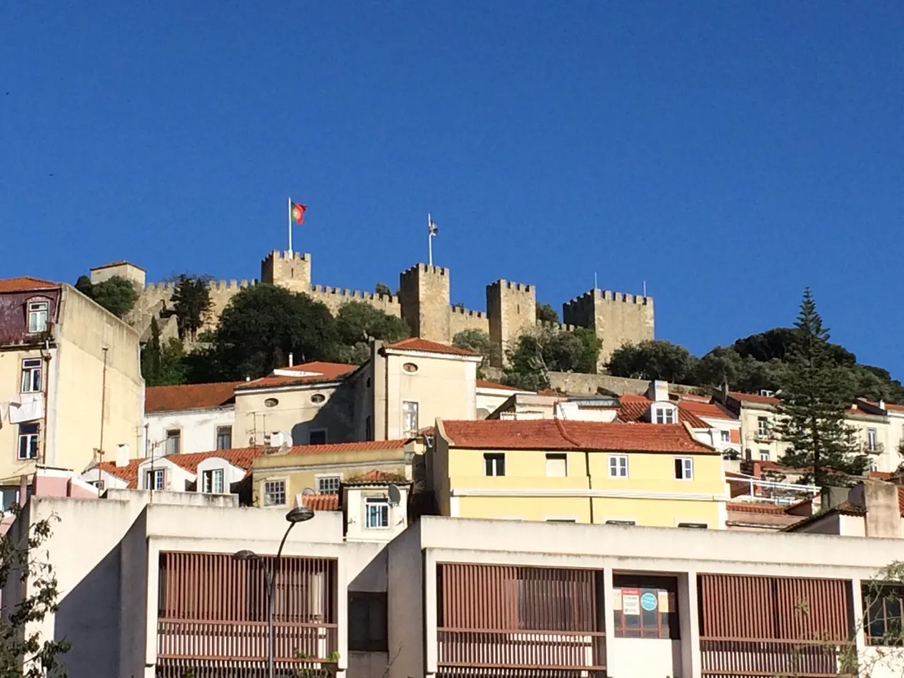 Kasteel São Jorge op de heuvel boven de gele en witte huizen van Lissabon