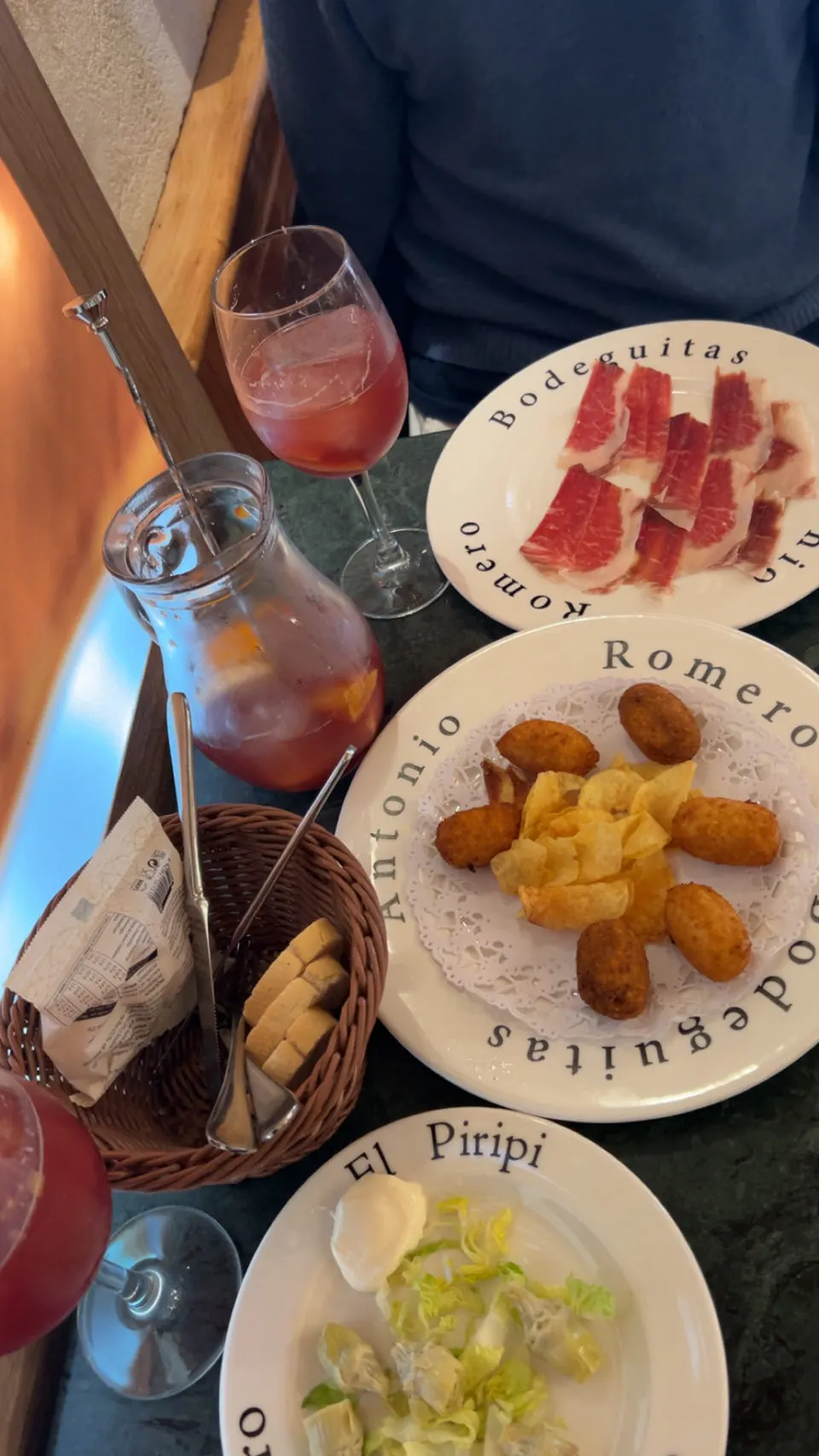 Een bord jamón, kroketten en chips met een glas en kan sangria in Sevilla