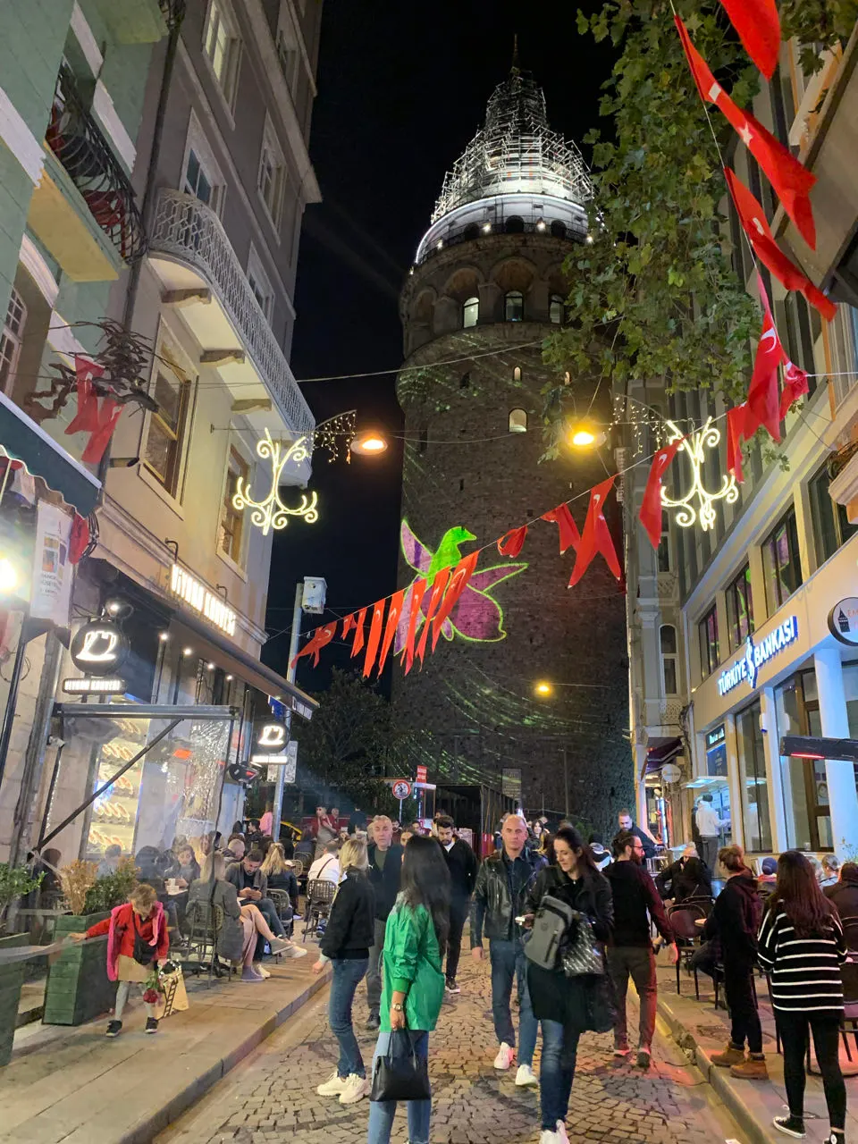 De verlichte Galata Toren in Istanbul in de avond, met Turkse vlaggen op de voorgrond