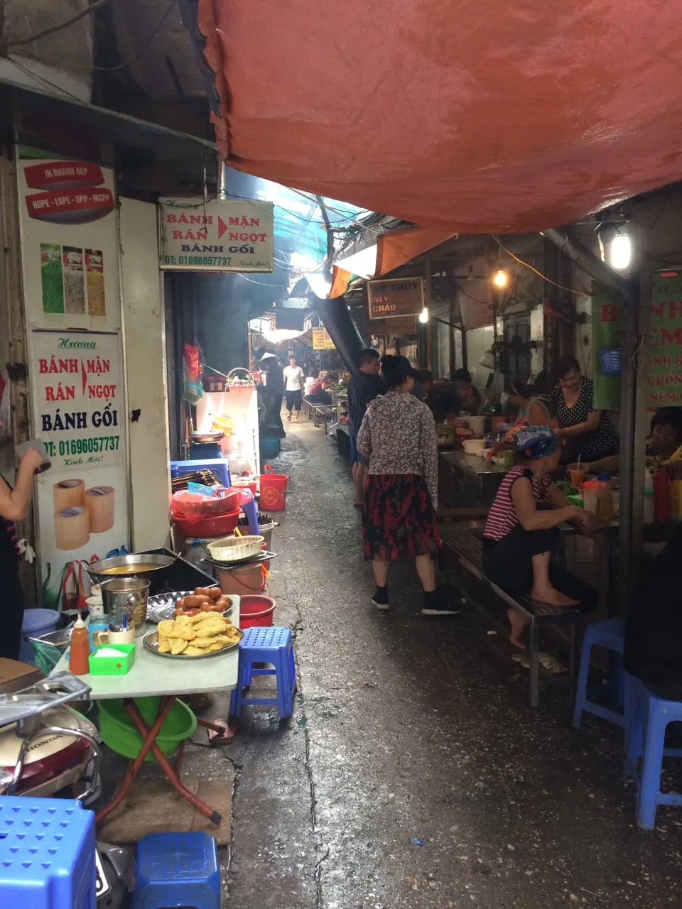 Straatkeuken met een eetkraam onder een rood zeil in Hanoi