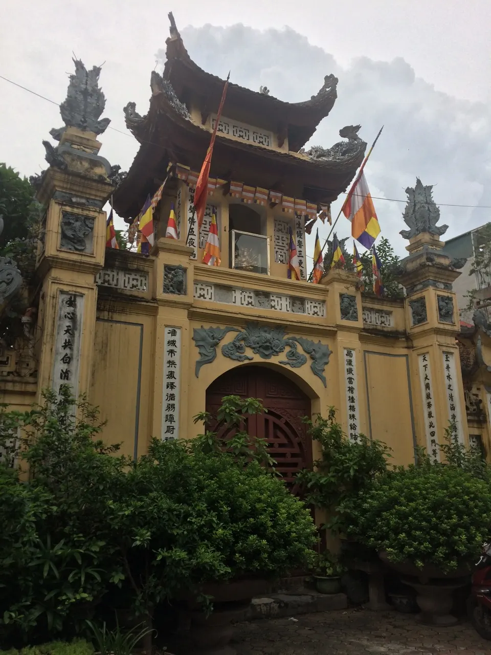 Gele tempelpoort met Vietnamese details tussen het groen in Hanoi