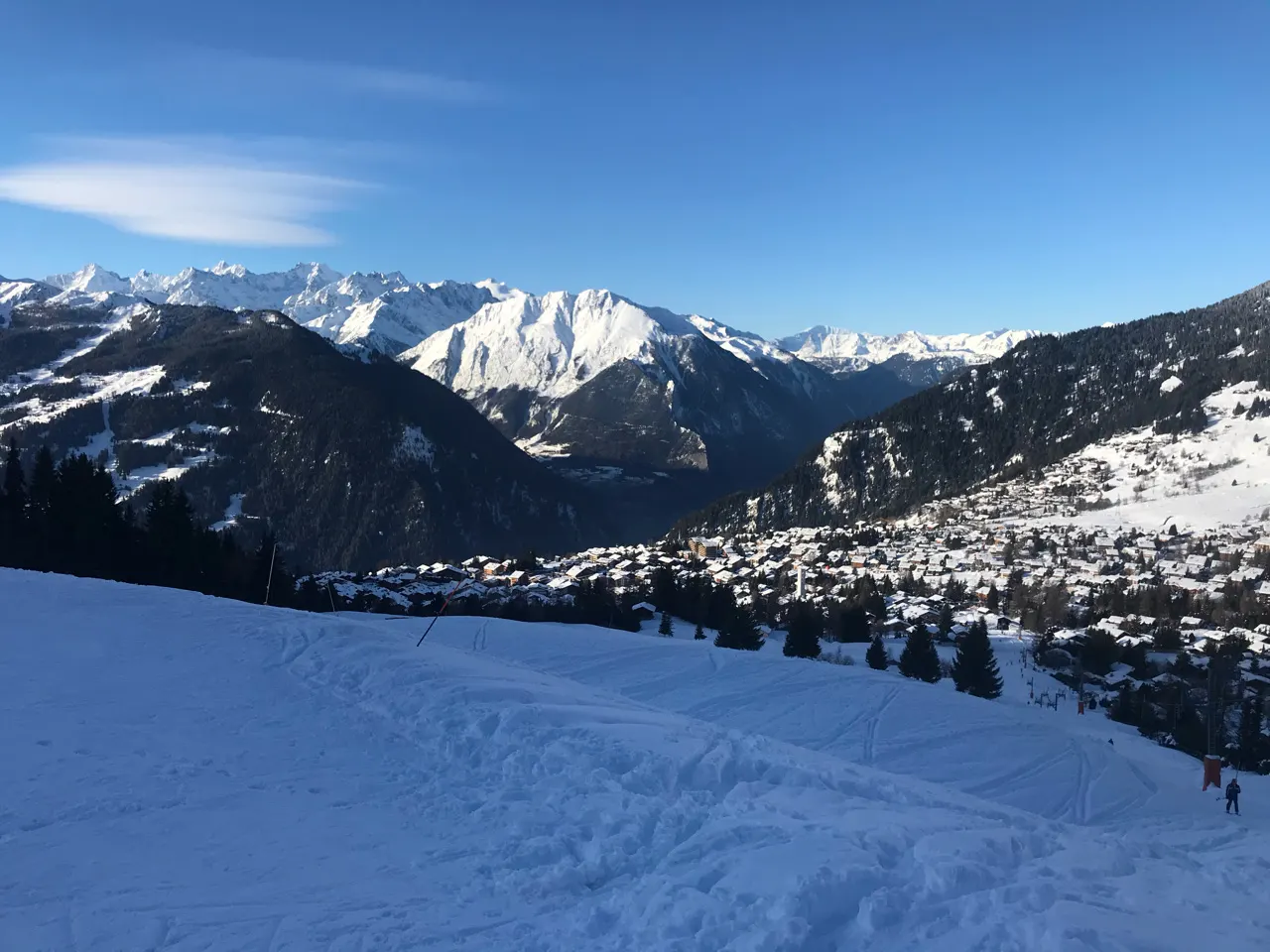 Wijds bergpanorama met besneeuwde toppen en het dal onder een blauwe lucht