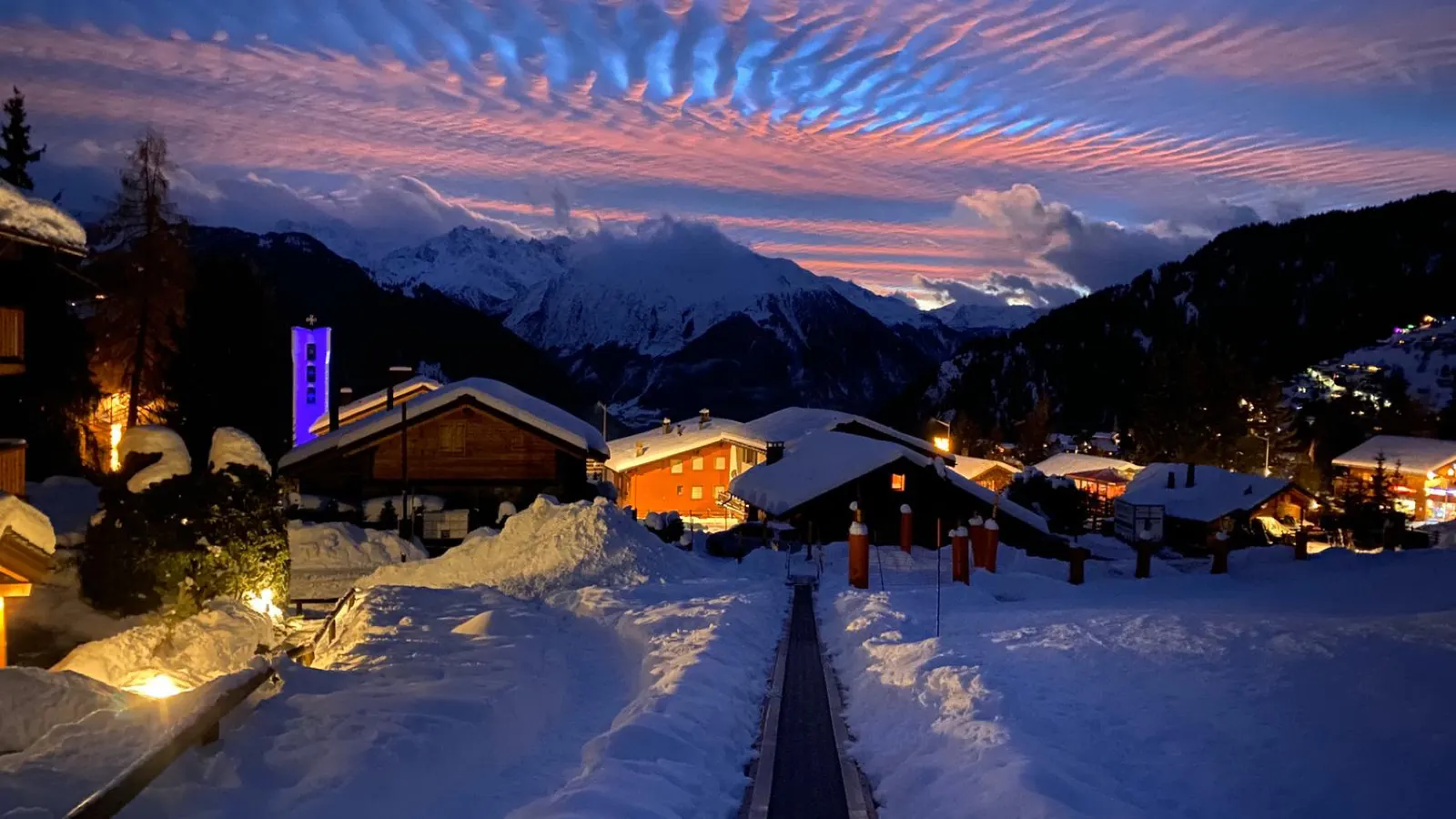 Het bergdorp Verbier bij schemering met een roze lucht boven de besneeuwde bergen